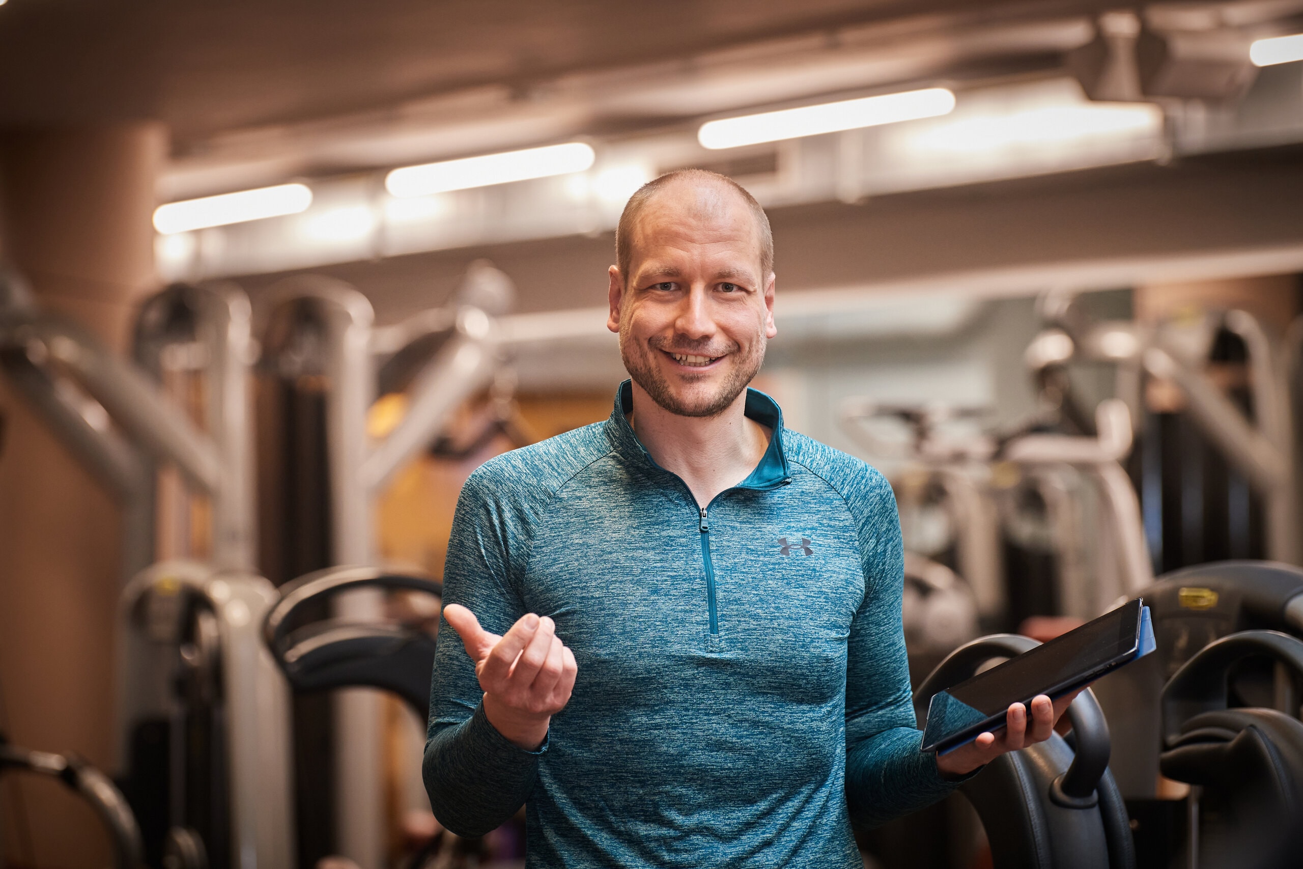 Ein Portrait von Christopher Schulz mit Tablet im Fitnessstudio